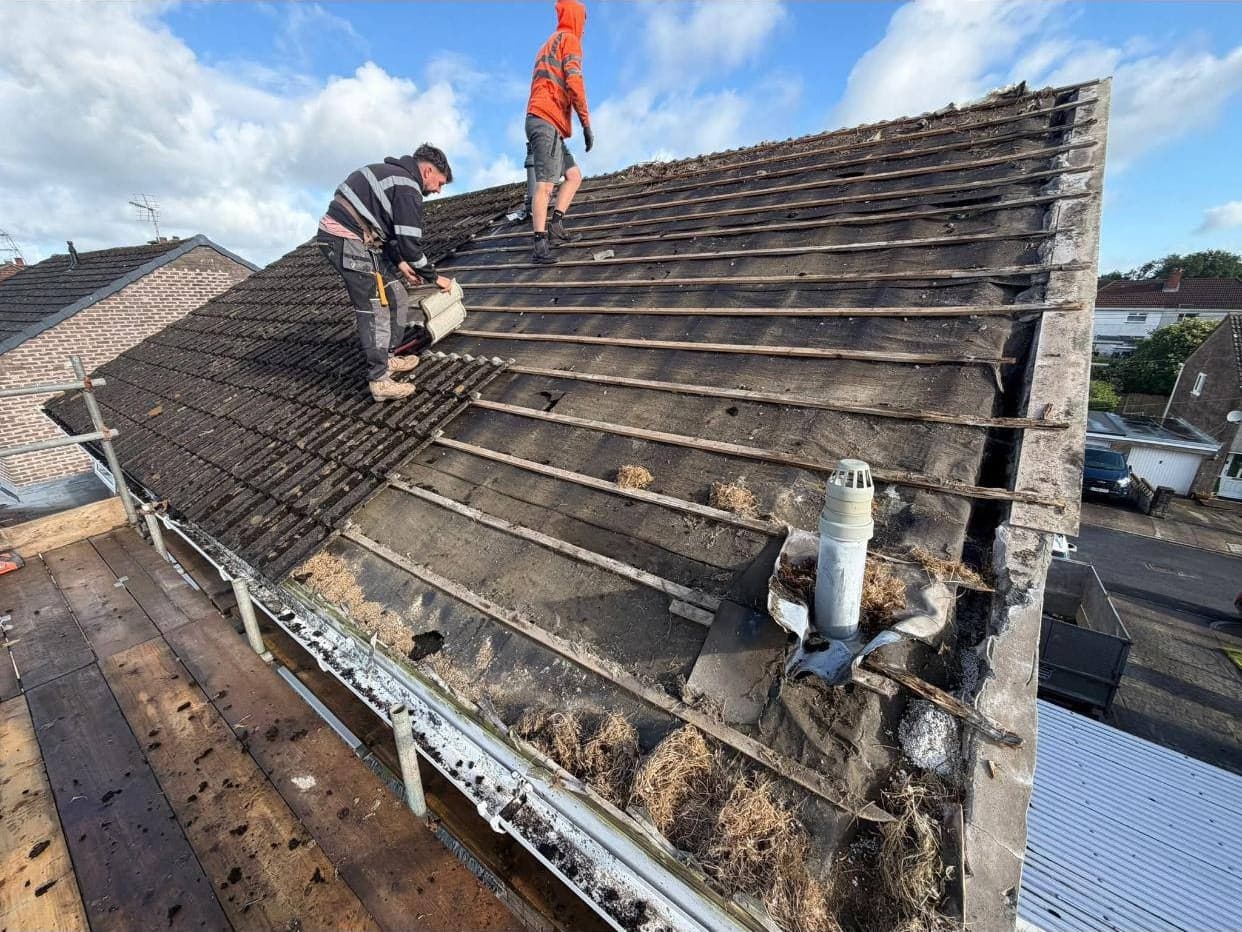 Two Midlands Roofing roofers stripping the old tiles off a pitched roof